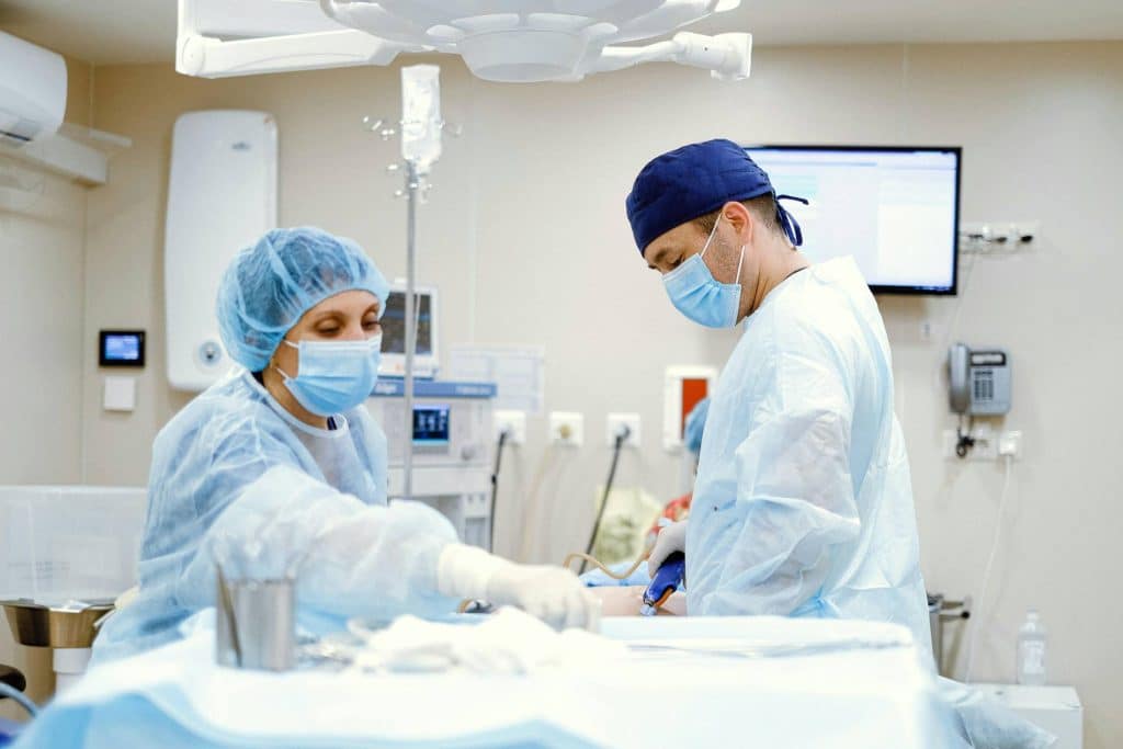 Two doctors in PPE working in an operating room. This image was chosen to represent a health system client FourFront has worked with.