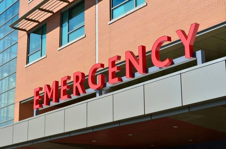 A red sign that reads "Emergency" on a brick hospital building.