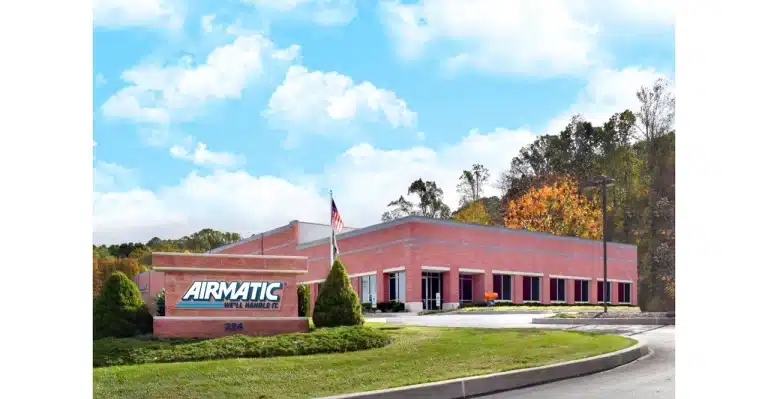 The AIRMATIC brick building with a flag and some grass.