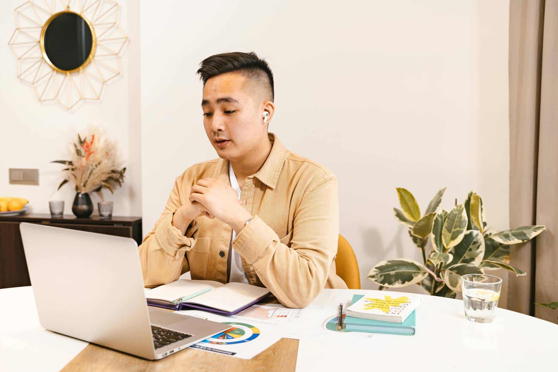 A person with short hair in a yellow sweater sits in front of a laptop, having an SEO consultation.